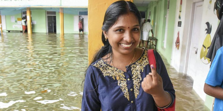 A woman shows her finger marked with indelible ink after casting her vote at a polling station inundated in rain water in Ernakulam
