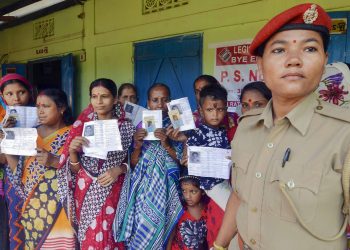 Women voters display their ID cards at a polling booth in Assam