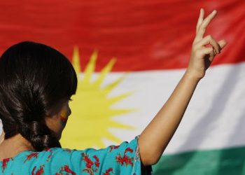 A protester in front of a Kurdish flag.