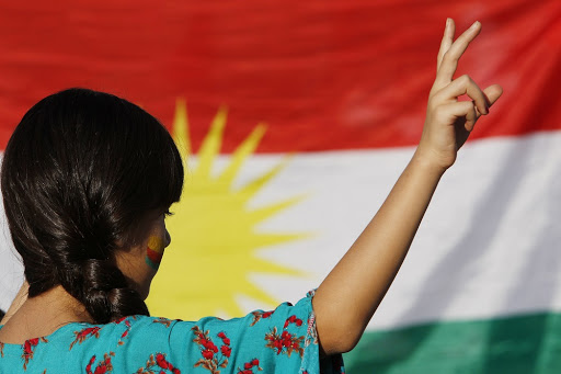 A protester in front of a Kurdish flag.