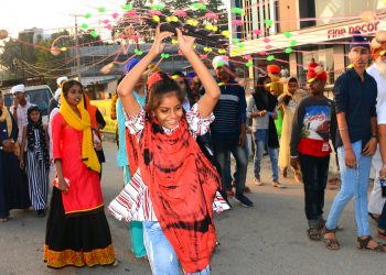 A girl swirling a decorative wheel during a procession for celebration of Guru Nanak Dev’s 550th birth anniversary in Sambalpur