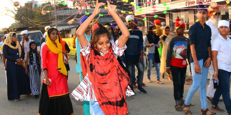 A girl swirling a decorative wheel during a procession for celebration of Guru Nanak Dev’s 550th birth anniversary in Sambalpur