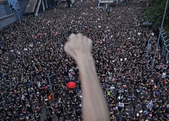 FILE - In this Sunday, June 16, 2019, file photo, a protester clenches his fist as tens of thousands of protesters march on the streets to stage a protest against the unpopular extradition bill in Hong Kong. (AP Photo/Vincent Yu, File)