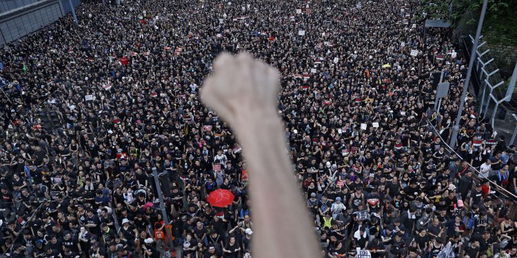 FILE - In this Sunday, June 16, 2019, file photo, a protester clenches his fist as tens of thousands of protesters march on the streets to stage a protest against the unpopular extradition bill in Hong Kong. (AP Photo/Vincent Yu, File)