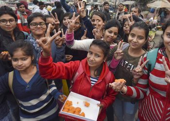 Children distribute sweets after the announcement of the verdict in the Nirbhaya gangrape case