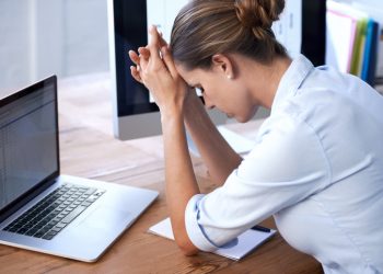 A young businesswoman sitting with her head in her hands