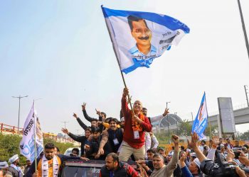 Manish Sisodia waves a flag as he celebrates along with his supporters after winning from the Patparganj Assembly seat