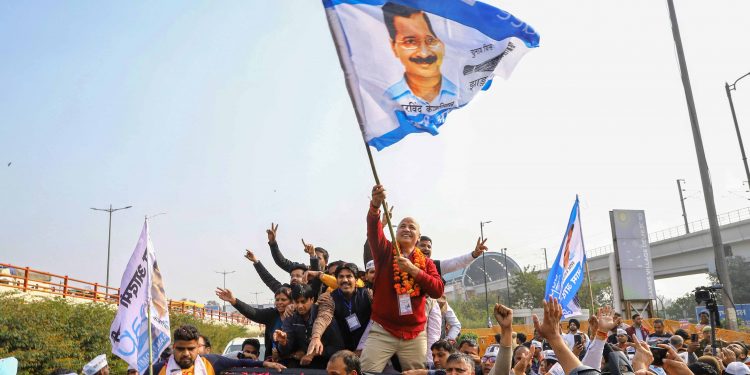Manish Sisodia waves a flag as he celebrates along with his supporters after winning from the Patparganj Assembly seat