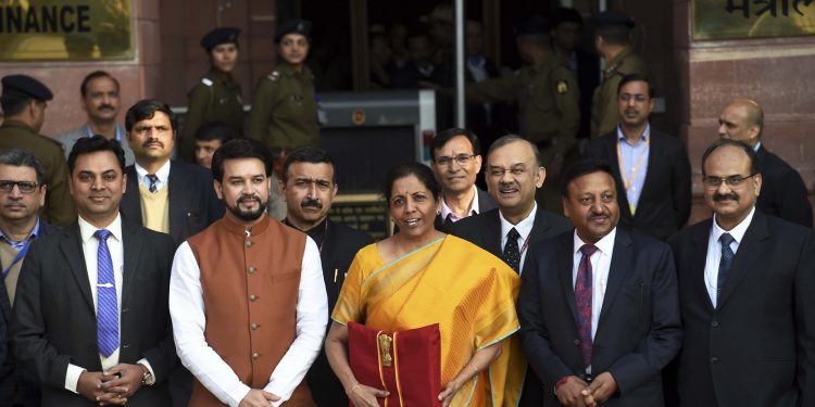 Union Finance Minister Nirmala Sitharaman, holding a folder containing the Union Budget documents, poses for photographers along with her deputy Anurag Thakur and other officials outside the Ministry of Finance office