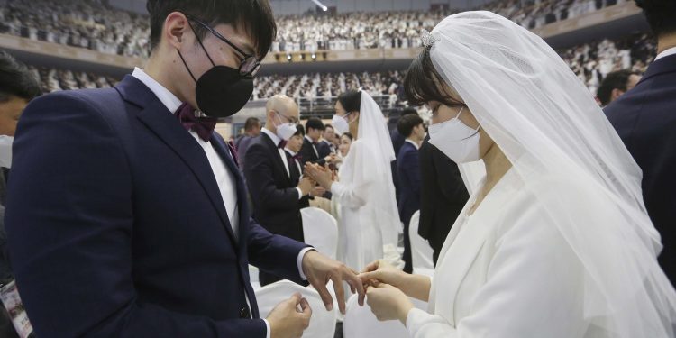 A couple wearing face masks exchanges their rings in a mass wedding ceremony at the Gapyeong in South Korea