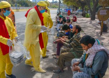 Volunteers distribute food to migrant workers in Noida Tuesday