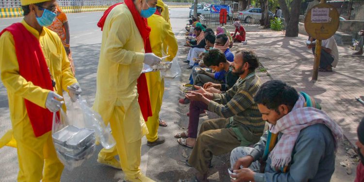 Volunteers distribute food to migrant workers in Noida Tuesday