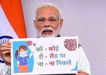 Prime Minister Narendra Modi holds a banner addresses the nation on the coronavirus pandemic, Tuesday