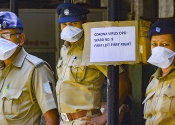 Security personnel wear protective masks as they wait outside the isolation ward of a Mumbai hospital