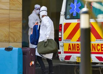 A medical worker and a suspected coronavirus affected person, both wearing protective suits at the Safdarjung hospital in New Delhi