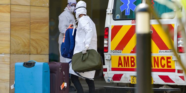 A medical worker and a suspected coronavirus affected person, both wearing protective suits at the Safdarjung hospital in New Delhi