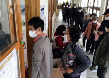 People wearing face masks to help protect against the spread of the new coronavirus wait in line to cast for their votes for the parliamentary elections at a polling station in Nonsan, South Korea, Wednesday, April 15, 2020. South Korean voters wore masks and moved slowly between lines of tape at polling stations on Wednesday to elect lawmakers in the shadows of the spreading coronavirus. (Kang Jong-min/Newsis via AP)