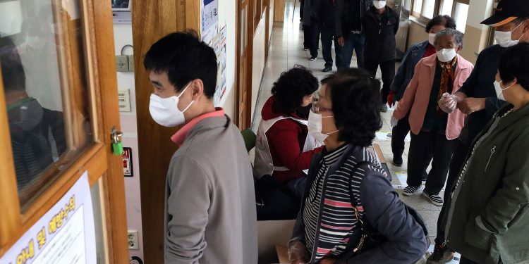 People wearing face masks to help protect against the spread of the new coronavirus wait in line to cast for their votes for the parliamentary elections at a polling station in Nonsan, South Korea, Wednesday, April 15, 2020. South Korean voters wore masks and moved slowly between lines of tape at polling stations on Wednesday to elect lawmakers in the shadows of the spreading coronavirus. (Kang Jong-min/Newsis via AP)