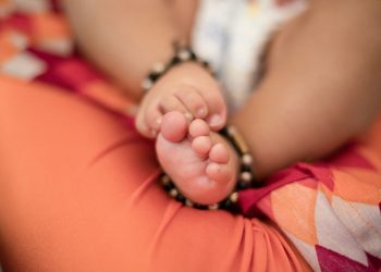 Close-up of baby girl feet sleeping on lap