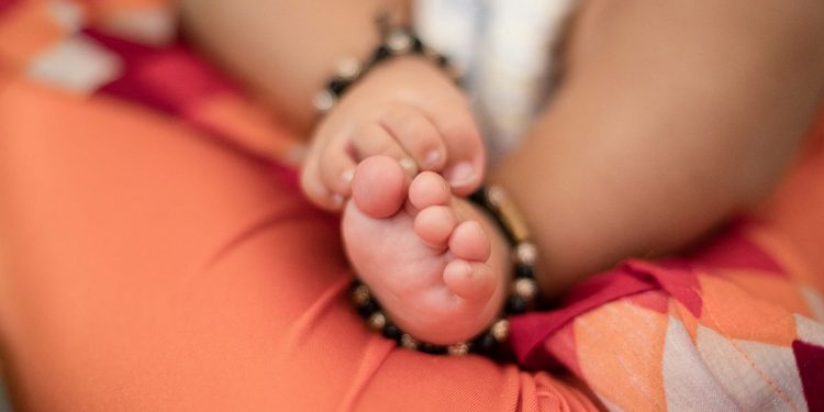 Close-up of baby girl feet sleeping on lap
