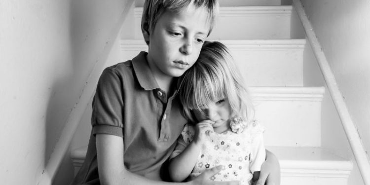 Upset Brother comforting his baby sister.