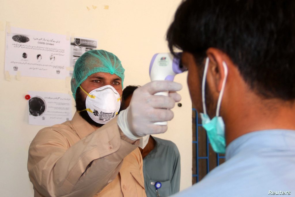 A health worker takes the temperature of a man who returned from Iran and is under medical observation, after Pakistan sealed its border with Iran as a preventive measure following the coronavirus outbreak, at the border post in Taftan, Pakistan February 25, 2020. REUTERS/Naseer Ahmed