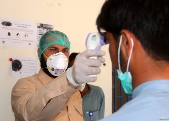 A health worker takes the temperature of a man who returned from Iran and is under medical observation, after Pakistan sealed its border with Iran as a preventive measure following the coronavirus outbreak, at the border post in Taftan, Pakistan February 25, 2020. REUTERS/Naseer Ahmed