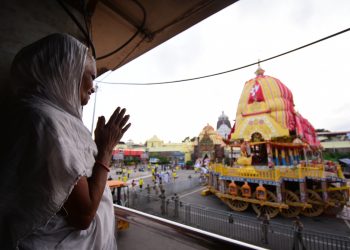 An elderly woman offers prayers to Lord Jagannath from a distance near Srimandir