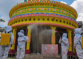 Members of committee Durga Puja wearing PPE kit sanitise a puja pandal in the wake of coronavirus pandemic. (Photo: PTI)