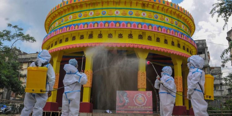 Members of committee Durga Puja wearing PPE kit sanitise a puja pandal in the wake of coronavirus pandemic. (Photo: PTI)