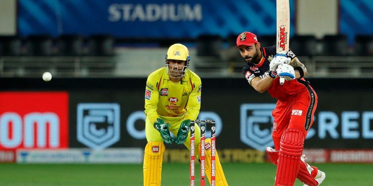 Virat Kohli drives through the cover region as CSK captain MS Dhoni looks on