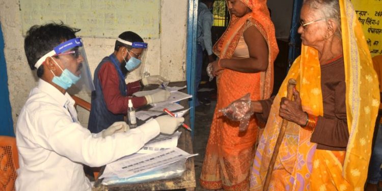 Rohtas: Polling officials check the names of voters at a polling booth as they arrive to cast their votes for the first phase of Bihar Assembly Election, amid the coronavirus pandemic, at Chenari police station in Rohtas district, Wednesday, Oct. 28, 2020. (PTI Photo)