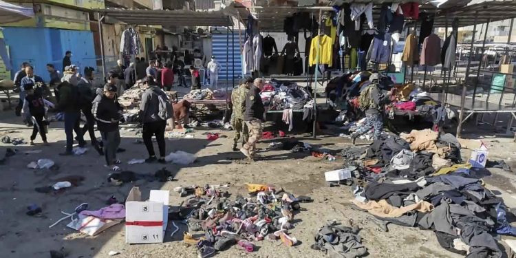 People and security forces gather at the site of a deadly bomb attack in a market selling used clothes, Iraq, Thursday, Jan. 21, 2021. Twin suicide bombings hit Iraq's capital Thursday killing and wounding civilians, police and state TV said. (AP Photo/Hadi Mizban)