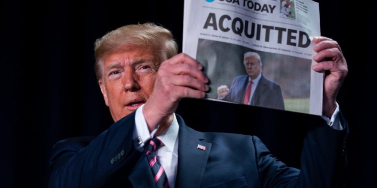 FILE – In this February 6, 2020, file photo, President Donald Trump holds up a newspaper with the headline that reads “ACQUITTED” at the 68th annual National Prayer Breakfast, at the Washington Hilton in Washington. (AP Photo/ Evan Vucci, File)