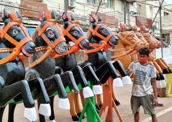 A servitor paints wooden horses ahead of the Rath Yatra in Puri, Sunday