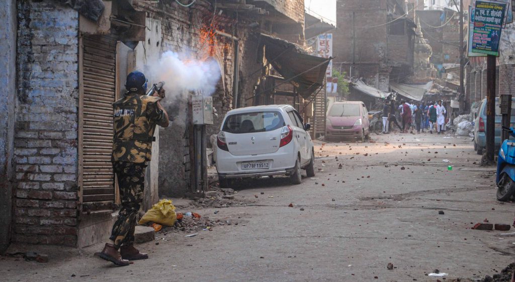 Police personnel use tear gas to disperse people amid clashes in Kanpur, Friday