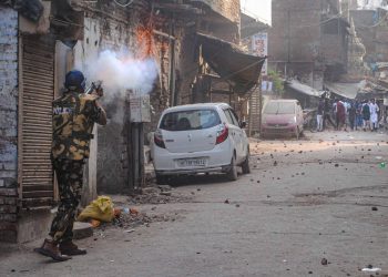 Police personnel use tear gas to disperse people amid clashes in Kanpur, Friday