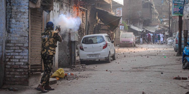 Police personnel use tear gas to disperse people amid clashes in Kanpur, Friday