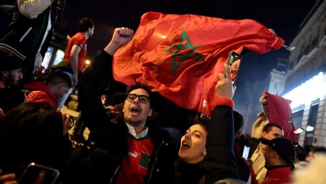 Morocco's supporters wave national flags to celebrate their victory after the Qatar 2022 World Cup football match between Morocco and Spain on the Champs Elysees in Paris on December 6, 2022.  (Photo by JULIEN DE ROSA / AFP)
