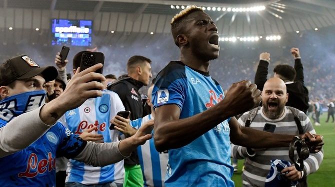 Napoli fans join Napoli's Nigerian forward Victor Osimhen (C) as he celebrates after the Italian Serie A football match between Udinese and Napoli on May 4, 2023 at the Friuli stadium in Udine.  Napoli ended a 33-year wait to win Italy's Serie A on May 4 after a 1-1 draw at Udinese secured their third league title and emulated the great teams led by Diego Maradona. (Photo by Andrea STACCIOLI / AFP)