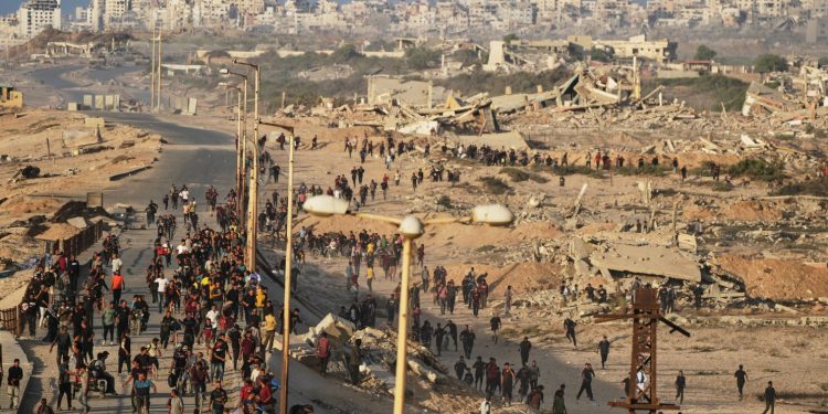 Israeli tanks are positioned on the coastal road leading to Gaza City as displaced Palestinians gather near Wadi Gaza in the central Gaza Strip, Thursday, Oct. 9, 2025. (AP Photo/Abdel Kareem Hana)
