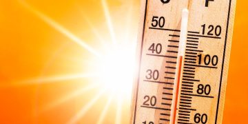 Background for a hot summer or heat wave, orange sky with with bright sun and thermometer